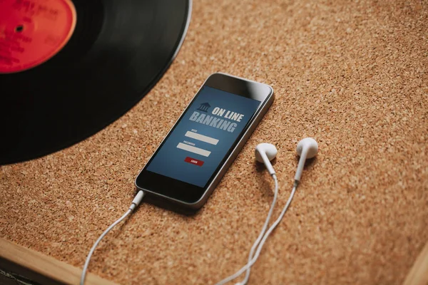 Mobile phone with on line mobile banking app in the screen, white earphones, and copy space. — Stock Photo, Image