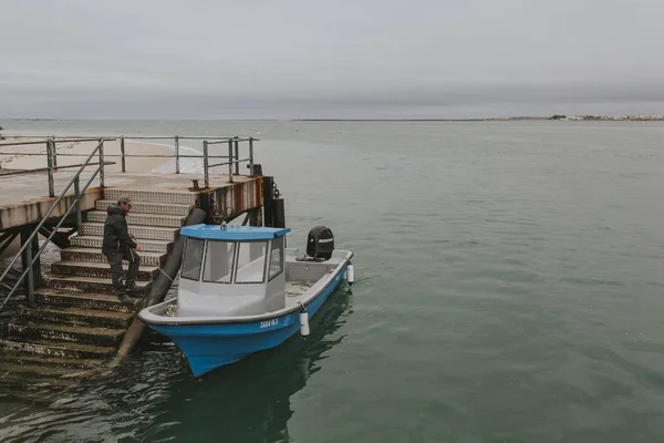 Armona Island, Portugalsko - 23. března 2018: Muž stravování v modré lod na ostrov Armona pier v zamračený den, Olhäo, Portugalsko. — Stock fotografie