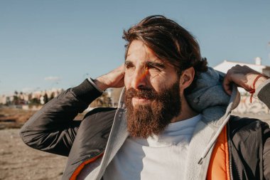 Genç adam öğe, dikey, güneşin yüzüne, kentsel sokak stil giyim sakallı.