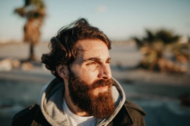 Genç adam öğe, dikey, güneşin yüzüne, kentsel tarzı kıyafetler üzerinde sakallı.