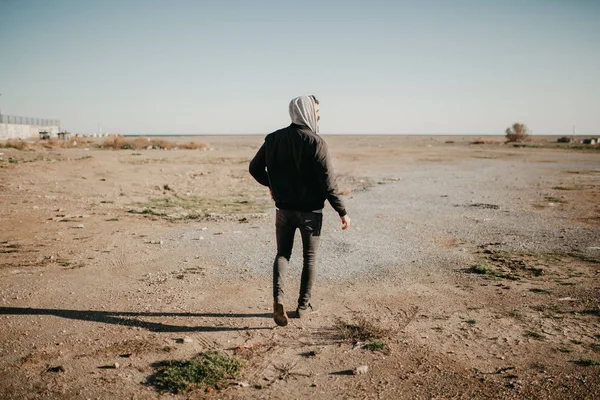 Jovem caminhando ao ar livre ao pôr do sol com estilo de roupa rapper urbano . — Fotografia de Stock