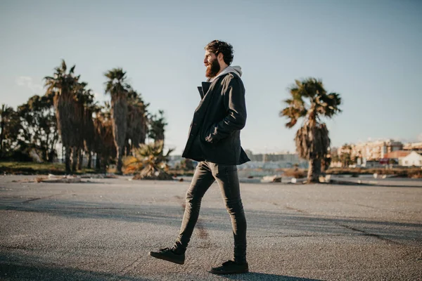 Young man walking outdoors at sunset with urban clothes style.