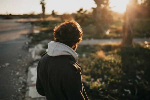 Giovane uomo barbuto sulla schiena guardando il tramonto all'aperto indossando abiti in stile urbano . — Foto Stock