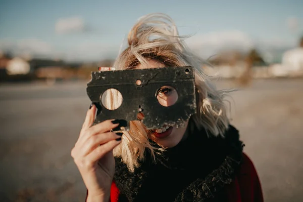 Blonde alternative woman playing with a VHS tape outdoors at sunset. Creative filmmaker concept. — Stock Photo, Image