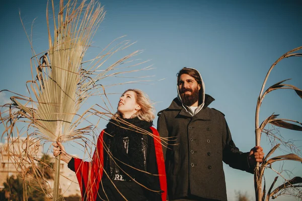 Junges Paar posiert mit Pflanzenzweigen in der Hand. — Stockfoto