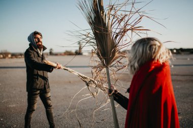 Genç güzel çift oynama ve açık havada palmiye ağacı dalları ile mücadele.