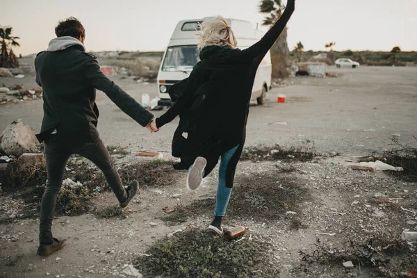 Alternativa casal de mãos dadas e correndo em direção a sua van com emoção . — Fotografia de Stock