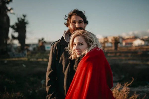 Close-up van portret van jonge alternatieve paar, buiten, bij zonsondergang, terwijl ze kijken naar de camera glimlachen. — Stockfoto