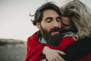 Sahilde kum oturan genç hippi çift romantik kucakladı.