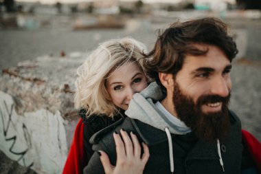 Sahilde kum oturan genç hippi çift romantik kucakladı.