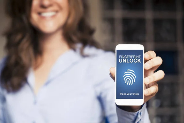 Leende kvinna håller en mobiltelefon med Fingerprint lås anmälan i skärmen. — Stockfoto