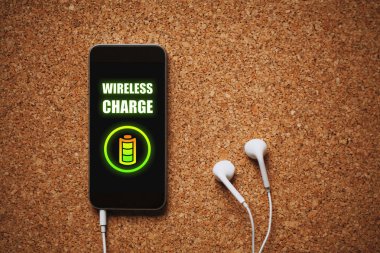 Cep telefonu ekran, beyaz kulaklık ve kopya alanı kablosuz şarj fonksiyonu ile.