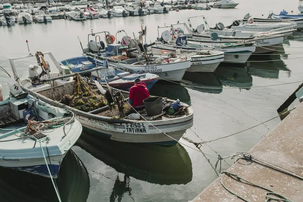 24. März 2018 - olhao, portugal: Fischer bei der Arbeit und Reparatur von Netzen in seinem Boot, angedockt am olhao dock, portugal, am 24. März 2018. — Stockfoto