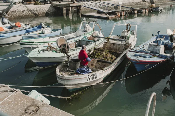 24. März 2018 - olhao, portugal: Fischer bei der Arbeit und Reparatur von Netzen in seinem Boot, angedockt am olhao dock, portugal, am 24. März 2018. — Stockfoto