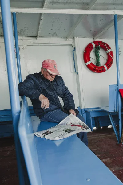 MARCH 24th, 2018 - OLHAO, PORTUGAL: Inside view of the public boat that connect the Portuguese city of Olho with Armona Island, during a regular trip and a sitting man reading news, on March 24th, 2018. — Stock Photo, Image