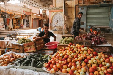 Rissani, Morocco - September 18th, 2019: Two men selling vegetables at the food market in Rissani, Morocco