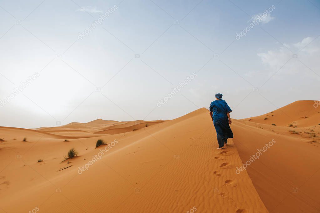 Desert dunes landscape with Arab man walking in the background.