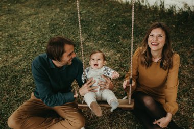 Mutlu aile portresi, baba bahçede mutlu bir çocuk tutuyor ve gülümseyen anne yukarı bakıyor..