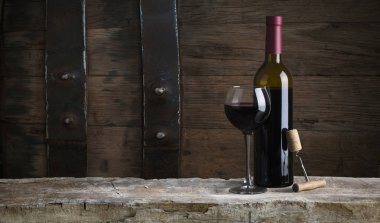 kırmızı şarap şişesi ve şarap kadehi yün fıçıda.