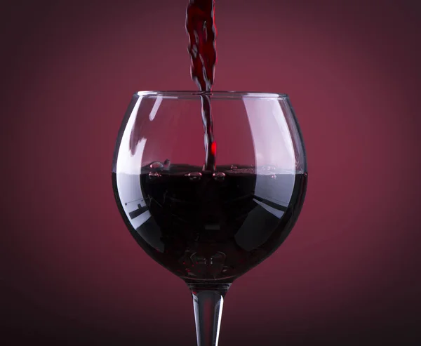 Vor hölzernem Hintergrund Rotwein ins Glas gießen — Stockfoto