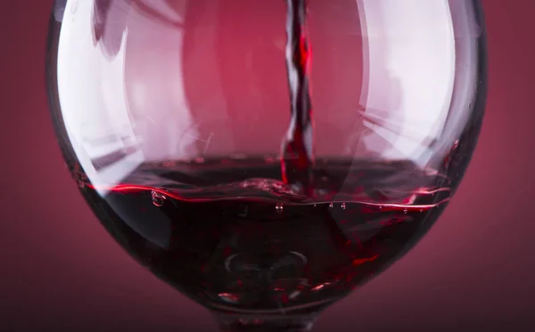 Wlewanie czerwonego wina do szklanki na drewnianym tle — Zdjęcie stockowe