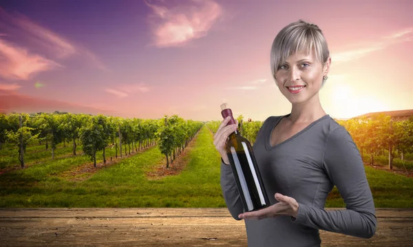 Joven chica descalza sosteniendo cesta de paja con una botella de vino sobre fondo natural — Foto de Stock