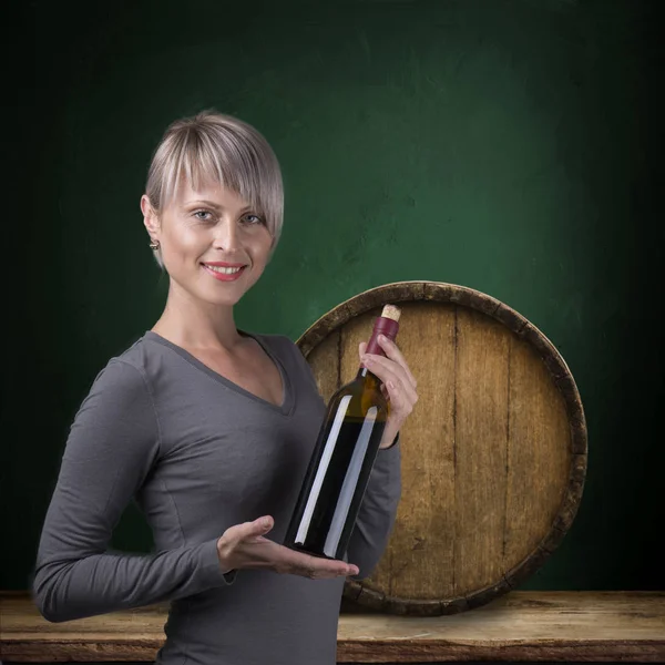 Joven chica descalza sosteniendo cesta de paja con una botella de vino sobre fondo natural — Foto de Stock
