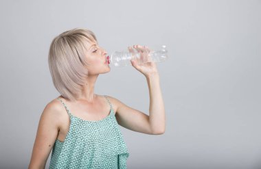 Bir elma ve bir su şişesi tutan mutlu genç kadın