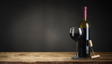 Kırmızı şarap ile bir tirbuşon bir şişe. Siyah bir ahşap arka plan üzerinde.