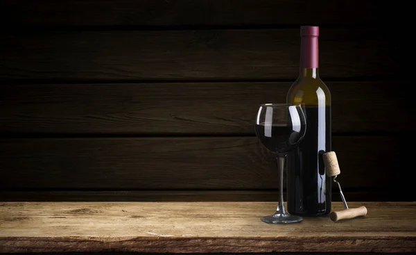 Bottle of red wine with a corkscrew. On a black wooden background. — Stock Photo, Image