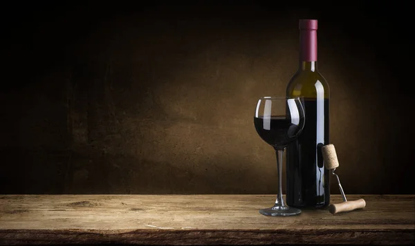 Bottle of red wine with a corkscrew. On a black wooden background. — Stock Photo, Image