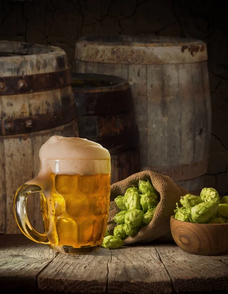 Oktoberfest beer barrel and beer glasses with wheat and hops on wooden table