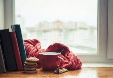 Bir fincan kahve veya çay, akıllı telefon ve kulaklık ile bir pencere yakınında sonbahar yaprakları. Sonbahar playlist kavramı. Yağmurlu günler için sonbahar müzik.