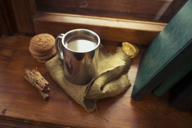 Cozy kış Natürmort: bir fincan sıcak çay ve vintage pencere dışında kar manzara karşı açılan kitap.