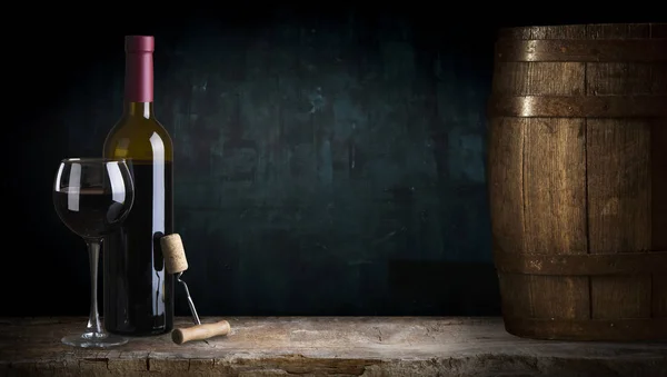 Бутылка красного вина и бокал вина на водяной бочке — стоковое фото