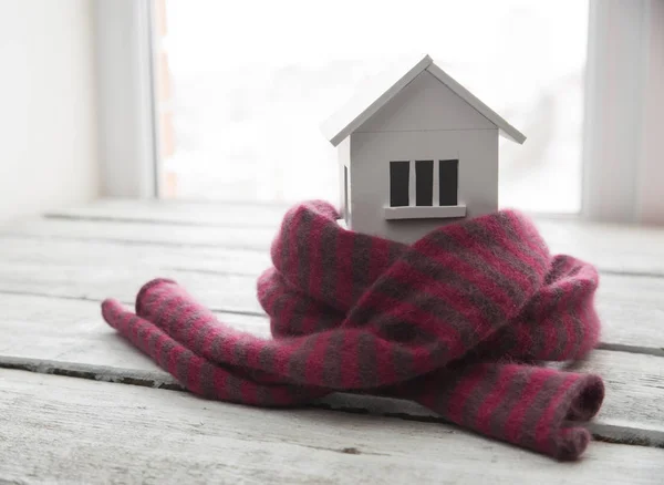 House in winter - heating system concept and cold snowy weather with model of a house wearing a knitted cap — Stock Photo, Image