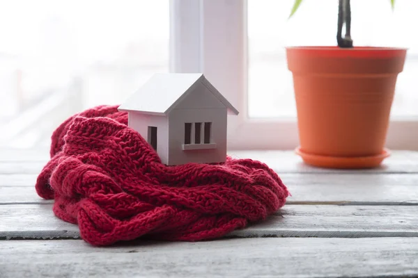 Casa no inverno - conceito de sistema de aquecimento e tempo nevado frio com modelo de uma casa usando um boné de malha — Fotografia de Stock