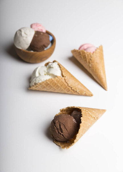 Variety of ice cream scoops in cones with chocolate, vanilla and strawberry