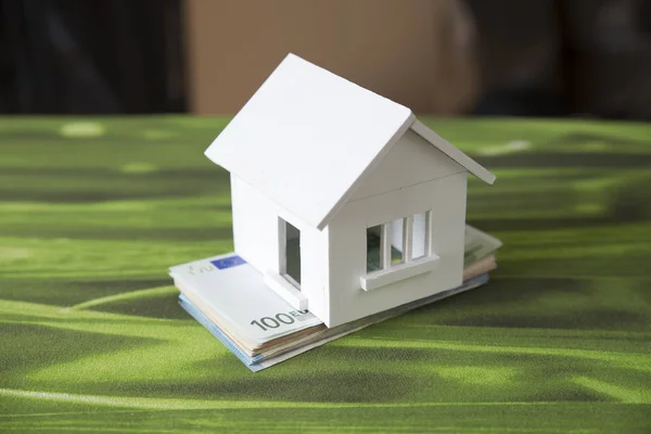 Business loans for real estate concept, a money bags put in a model home on the table on bokeh background in the public park. — Stock Photo, Image