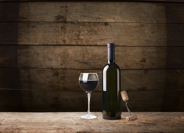Pouring red wine into the glass against wooden background — Stock Photo, Image