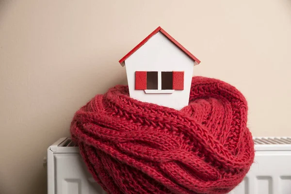 Casa no inverno - conceito de sistema de aquecimento e tempo nevado frio com modelo de uma casa usando um boné de malha — Fotografia de Stock