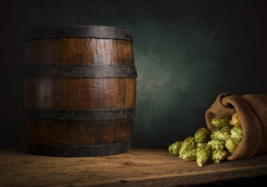 Bira fıçısı ve bira bardakları tahta bir masada. Koyu kahverengi arkaplan.