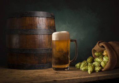 Bira fıçısı ve bira bardakları tahta bir masada. Koyu kahverengi arkaplan.