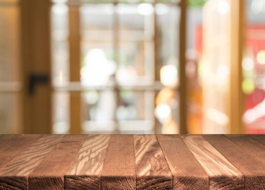 Boş kahverengi ahşap masa ve insanların yemekten hoşlandıkları, montaj için veya ürünlerinizi sergilemek için kullanılabilecek olan rezidans ışıklarının bulanık arkaplanı