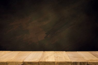 Seçili odak boş kahverengi ahşap masa ve duvar dokusu veya eski siyah tuğla duvar arkaplan bulanık görüntüsü. Fotomontaj ya da ürün gösterimi için