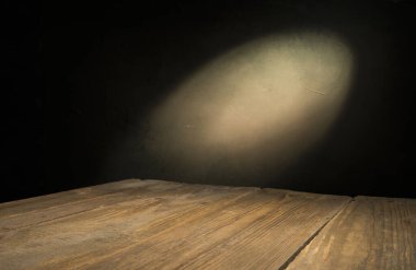 Karanlık oda arka planında bulanık beton duvar olan eski ahşap masa..