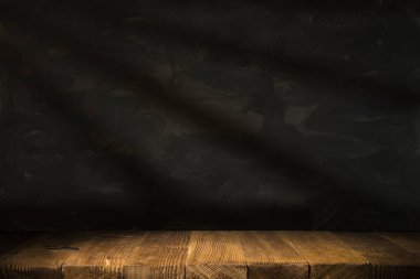 Karanlık oda arka planında bulanık beton duvar olan eski ahşap masa..