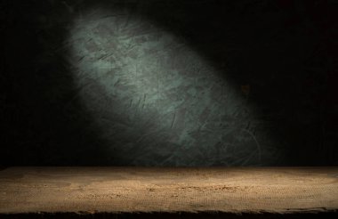 Karanlık oda arka planında bulanık beton duvar olan eski ahşap masa..