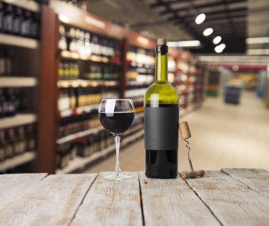 Şarap şişelerinin yanında duran barmen ya da erkek barmen bir bardak şarap tutuyor, renge bakıyor ve kadehteki şarap kokusunu alıyor..