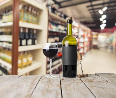 Şarap şişelerinin yanında duran barmen ya da erkek barmen bir bardak şarap tutuyor, renge bakıyor ve kadehteki şarap kokusunu alıyor..